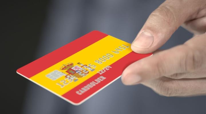 tarjeta bancaria ficticia con bandera de España y datos inventados; bloqueo de transferencias por falta de documentación